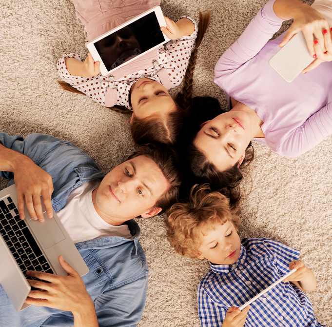 A group of children lying down together and using their technology devices